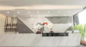 two people standing at a counter in a lobby at Borrman Hotel Fangchenggang High-speed Railway North Station Crystal International in Fangcheng