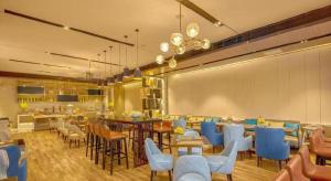 a restaurant with blue chairs and a dining room at Echarm Hotel Liuzhou High-speed Railway Station in Liuzhou