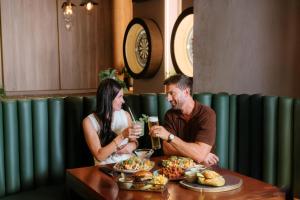ein Mann und eine Frau sitzen an einem Tisch mit Essen in der Unterkunft JA Ocean View Hotel, Jumeirah Beach Dubai in Dubai