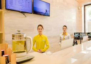 zwei Frauen stehen an einer Theke in einem Raum in der Unterkunft City Comfort Inn Nanchang Bayi Square Dinggong Road in Nanchang