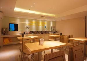 un restaurant vide avec des tables et des chaises en bois dans l'établissement City Comfort Inn Zhanjiang Middle Renmin Avenue Dingsheng Square, à Zhanjiang