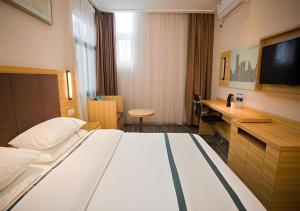 a hotel room with a bed and a flat screen tv at City Comfort Inn Deyang Wenmiao Square Gymnasium in Deyang