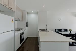 a kitchen with white cabinets and a counter top at Urban 1-Bed Apartment in the Heart of the City in Canberra