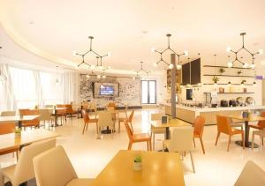 a dining room with tables and chairs and a kitchen at City Comfort Inn Nantong Qidong Renmin Zhong Road Xingfudao in Huilongzhen