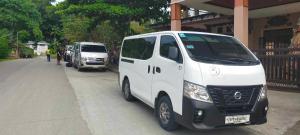zwei weiße Vans, die an einer Straße geparkt sind in der Unterkunft Van Rental COUNTRYSIDE TOUR IN BOHOL in Tagbilaran