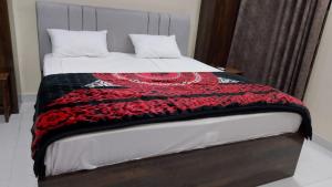 Spacious 2-Bedroom Apartment with Terrace & Multiple Bathrooms في Dargai: سرير عليه بطانية حمراء وسوداء