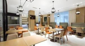 a dining room with tables and chairs and lights at City Comfort Inn Lingshui Central Avenue Bus Station in Lingshui