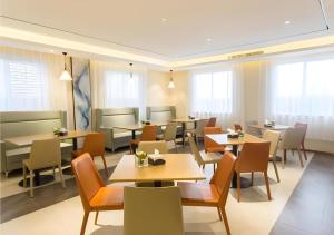a dining room with tables and chairs and windows at City Comfort Inn Guigang Zhongshan High Speed Railway Station in Guigang