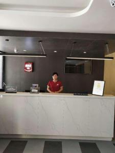 a man standing behind a counter in a restaurant at Thank Inn Plus Hotel Xinjiang Urumqi Tianshan District Bingtuan Erzhong in Ürümqi