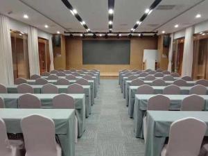 ein Konferenzraum mit Tischen und Stühlen und einer Leinwand in der Unterkunft James Joyce Coffetel Shijiazhuang Wanda Plaza Tangu Metro Station in Shijiazhuang