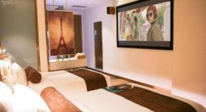 ein Schlafzimmer mit einem Bett und einem Fernseher an der Wand in der Unterkunft James Joyce Coffetel Shijiazhuang Wanda Plaza Tangu Metro Station in Shijiazhuang