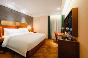 ein Schlafzimmer mit einem großen weißen Bett und einem Flachbildfernseher in der Unterkunft James Joyce Coffetel Tianjin Railway Station in Tianjin