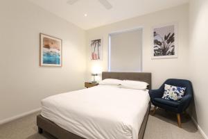 Un dormitorio con una cama y una silla azul. en Gorgeous 2-Bed Apartment By Shops and the River, en Batemans Bay