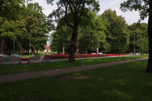 een park met bankjes en rode bloemen en bomen bij Jaukus butas Klaipėdos centre in Klaipėda +2 foto's
