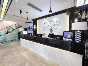 une femme debout à un comptoir dans un magasin dans l'établissement Xana Hotelle Shenzheng South Station Foxconn, à Tiantangwei