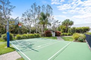 Una cancha de tenis en un patio con un aro de baloncesto en Beachside 3-Bed with BBQ, Pool, Gym & Tennis Court, en Marcoola