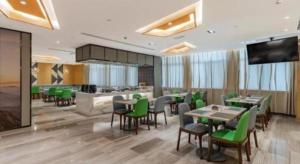 a restaurant with green chairs and tables and a kitchen at GreenTree Eastern Hotel Bengbu Huaishang District Yubo Garden in Bengbu