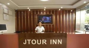 a woman is standing behind a desk in a jointiniini office at JTOUR Inn Zhanjiang Poly Yuandian Plaza in Zhanjiang