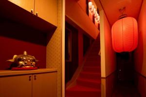 een gang met een trap met rode muren en een lantaarn bij The Kabuki-do Inn Haneda in Tokyo
