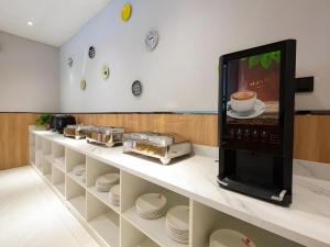 a kitchen with a microwave on a counter with plates at Shell Hotel Anhui Huaibei Suixi County Economic Development Zone in Suixi