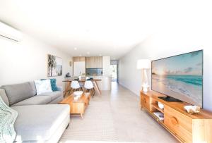 Una sala de estar con un televisor de pantalla plana grande. en Exquisite 1-Bed Apartment with Bay Views, en Batemans Bay
