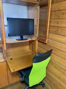 une chaise verte devant un bureau avec une télévision dans l'établissement THE HIDEOUT VILLA KUSATSU - Vacation STAY 90944v, à Kusatsu