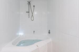 ein weißes Bad mit einer Eckbadewanne in der Unterkunft Lakeside 3-Bed Apartment with Jacuzzi in Belconnen