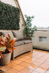 eine Korbcouch auf einer Terrasse mit Pflanzen in der Unterkunft Lakeside 3-Bed Apartment with Jacuzzi in Belconnen
