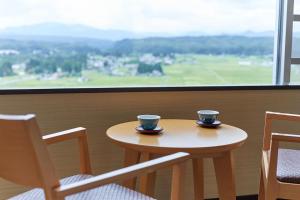 two cups sitting on a table in front of a window at KAMENOI HOTEL Ichinoseki in Ichinoseki