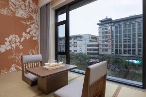 una stanza con un tavolo e sedie e una grande finestra di UrCove by Hyatt Xi'an Bell Tower Huimin Street Hotel a Xi'an