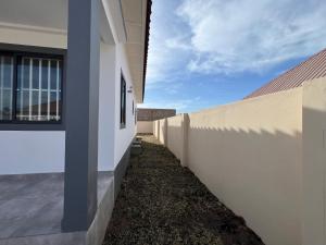 Una vista lateral de una pared blanca al lado de una valla. en TAF City Home, en Sifoe