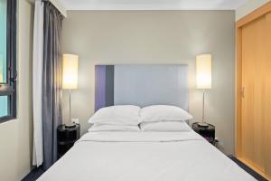 a bedroom with a large white bed with two lamps at Contemporary 1-Bed First Floor Unit with Pool in Sydney +3 photos