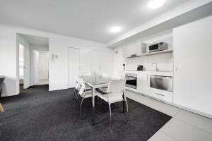 Una cocina con gabinetes blancos y una mesa y sillas. en Spacious 2-Bed Conveniently by Lake Tuggeranong, en Tuggeranong 7 fotos más