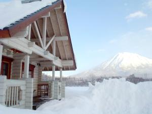 a snow covered house with a mountain in the background at Niseko Izumikyo in Kutchan