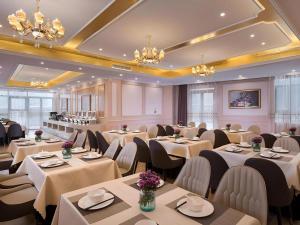 a dining room with tables and chairs and chandeliers at Vienna Hotel Xuzhou Junsheng Plaza Benteng Avenue Metro Station in Xuzhou