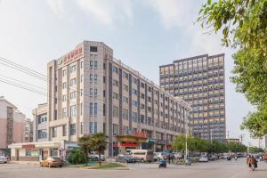 a large building on a city street with cars at Vienna Hotel Xuzhou Junsheng Plaza Benteng Avenue Metro Station in Xuzhou