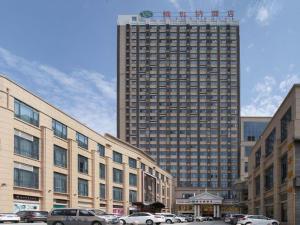 a large building with cars parked in front of it at Vienna Hotel Anhui Taihe Baitai Xingma International in Taihe
