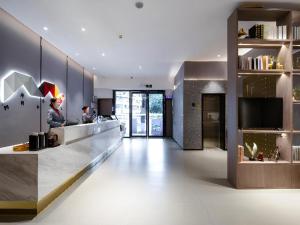 a lobby of a building with a counter and a person at Borrman Hotel Wuzhou College Fumin Road in Wuzhou