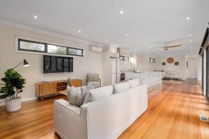 Una sala de estar con un sofá blanco y una cocina. en Luxurious 3-Bed Home with Outdoor Spa by Beach, en Tootgarook