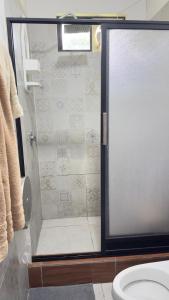 une douche avec une porte vitrée dans une salle de bain dans l'établissement Habitación master # 1, à Macas