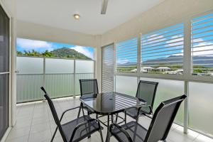 a dining room with a table and chairs on a balcony at Trinity Beach Retreat with Pool and Scenic Views in Trinity Beach