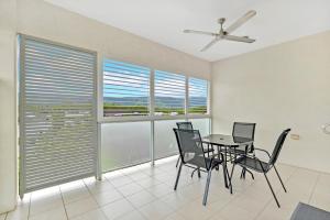 a dining room with a table and chairs and windows at Trinity Beach Retreat with Pool and Scenic Views in Trinity Beach