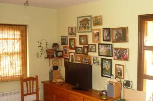 a room with a tv and a wall of pictures at Casa Nueva Carmen in Pendueles