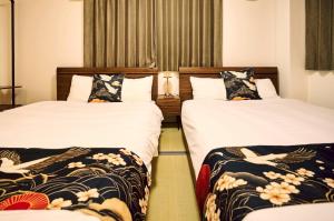 twee bedden in een hotelkamer met witte lakens bij The Kabuki-do Inn Haneda in Tokyo