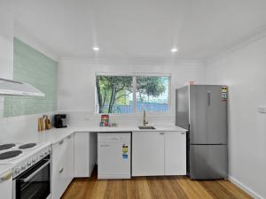 La cuisine est équipée de comptoirs blancs et d'un réfrigérateur en acier inoxydable. dans l'établissement Spacious 2-Bed Townhouse with BBQ by the Beach, à Surf Beach