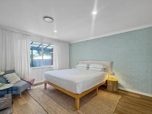 une chambre avec un lit blanc et un mur bleu dans l'établissement Spacious 2-Bed Townhouse with BBQ by the Beach, à Surf Beach