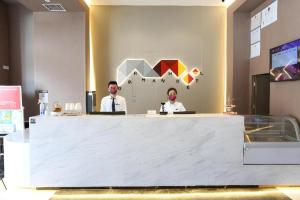 deux hommes assis à un comptoir dans une pièce dans l'établissement Borrman Hotel Wuhan Yellow Crane Tower Fuxing Road Metro Station, à Wuhan