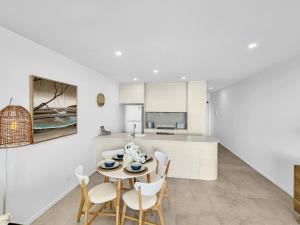 uma cozinha e sala de jantar com mesa e cadeiras em Modern 1-Bedroom Apt with Sweeping Water Views em Batemans Bay mais 15 fotografias