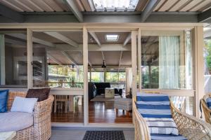 une terrasse couverte avec des chaises en osier et un salon dans l'établissement Secluded 3-Bed Retreat Moments to the Beach, à Surf Beach 40 autres photos