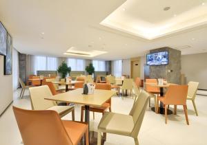 un restaurant avec des tables et des chaises et une télévision à écran plat dans l'établissement City Comfort Inn Wuhan Hankou Bei Light Rail Station, à Wuhan